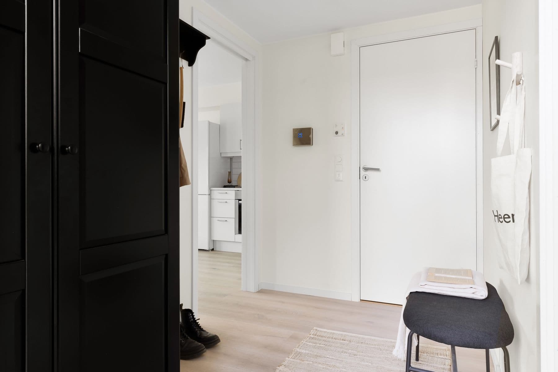 Ljus lägenhetshall med entrédörr och manöverpanel